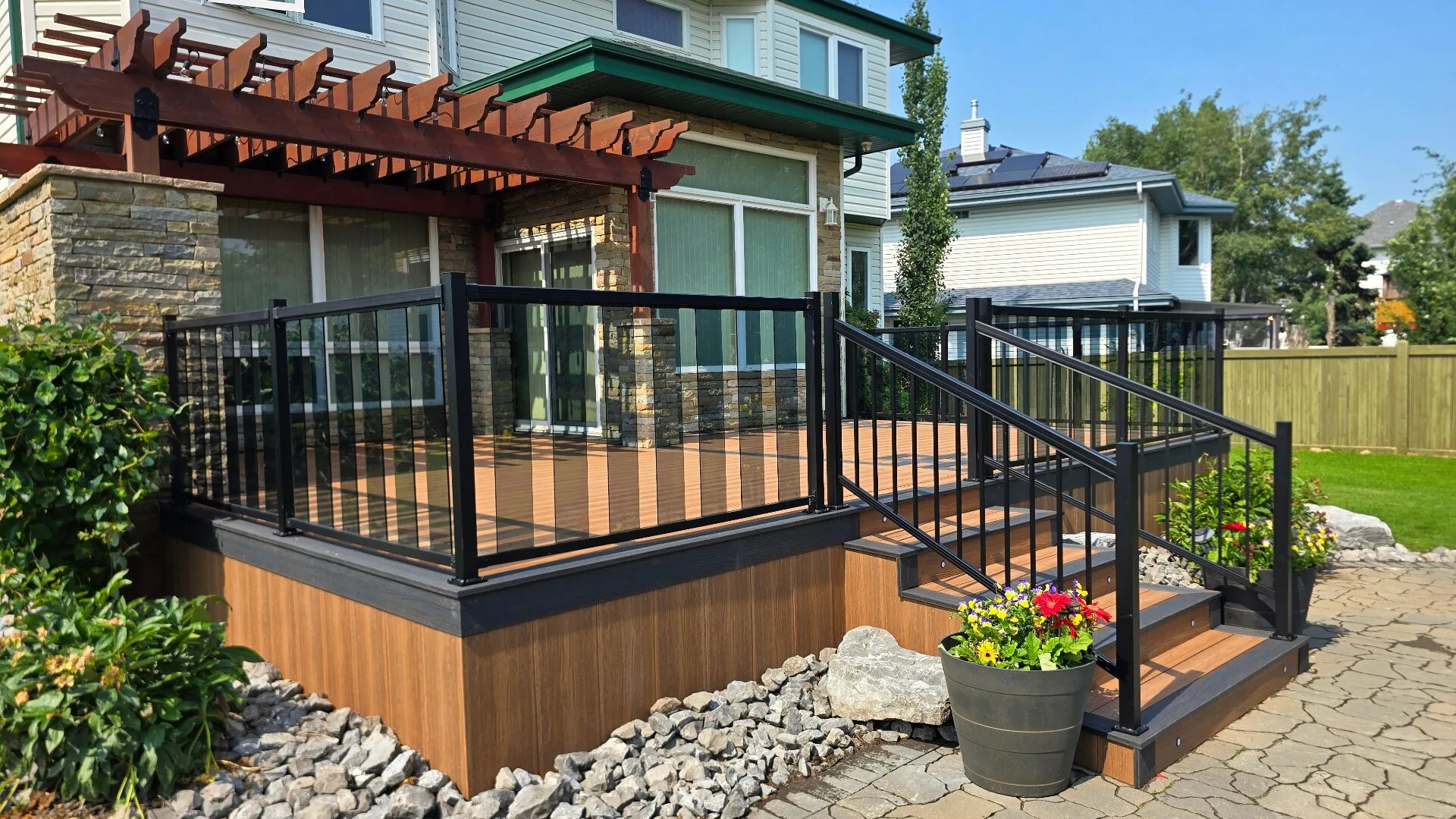 Composite deck with black glass railings, stairs, and attached pergola